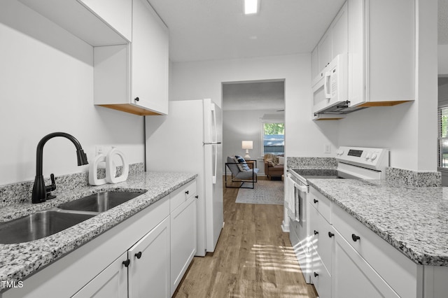 1613 Kilmer Ter, Durham, NC 27703 - kitchen with white appliances, white cabinets, light stone counters, a sink, and light wood-style flooring