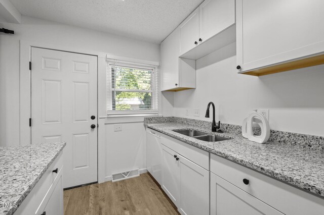 1613 Kilmer Ter, Durham, NC 27703 - kitchen featuring white cabinets, a sink, light wood-style floors, a textured ceiling, and visible vents