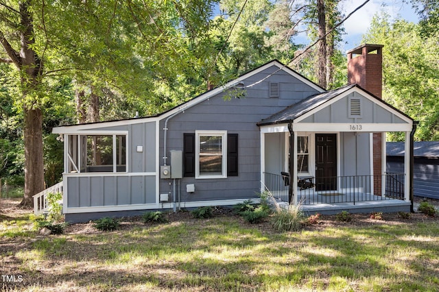 1613 Kilmer Ter, Durham, NC 27703 - bungalow-style home with covered porch, board and batten siding, a chimney, and a front lawn