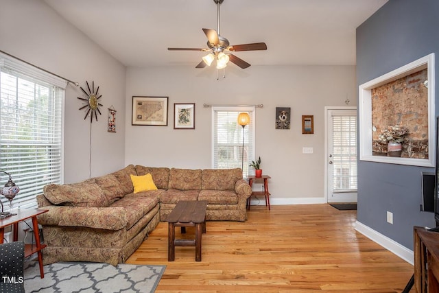 living room featuring baseboards, light wood-style floors, ceiling fan, and a healthy amount of sunlight