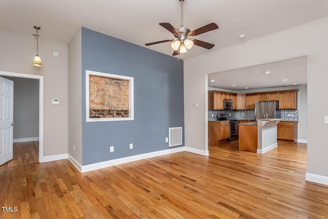 305 Freeman St, Raleigh, NC 27601 - kitchen featuring stainless steel appliances, brown cabinets, tasteful backsplash, light wood-type flooring, and ceiling fan