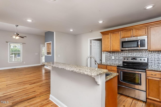 305 Freeman St, Raleigh, NC 27601 - kitchen featuring appliances with stainless steel finishes, decorative backsplash, brown cabinets, light wood finished floors, and recessed lighting