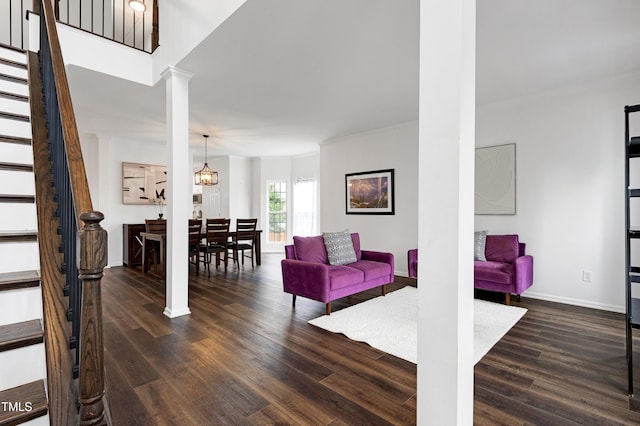 living area featuring decorative columns, stairway, wood finished floors, baseboards, and crown molding