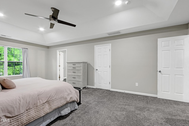 bedroom with a tray ceiling, dark carpet, baseboards, a ceiling fan, and recessed lighting