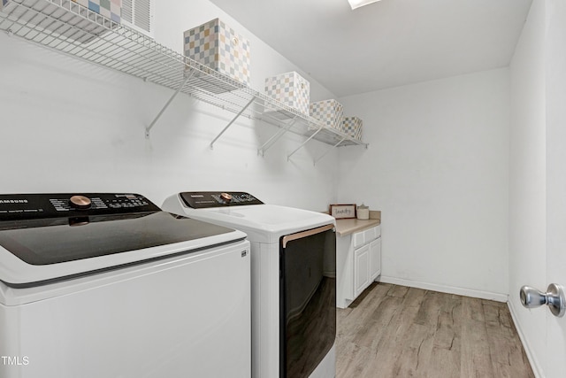 laundry room featuring light wood finished floors, washer and clothes dryer, baseboards, and cabinet space