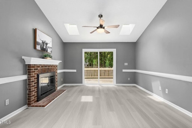 2402 Cynthia Dr, Durham, NC 27704 - unfurnished living room featuring vaulted ceiling with skylight, a ceiling fan, wood finished floors, baseboards, and a brick fireplace