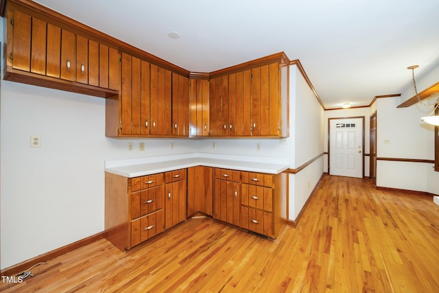 5800 Heatherbrook Cir, Raleigh, NC 27612 - kitchen with brown cabinetry, light wood finished floors, light countertops, baseboards, and ornamental molding