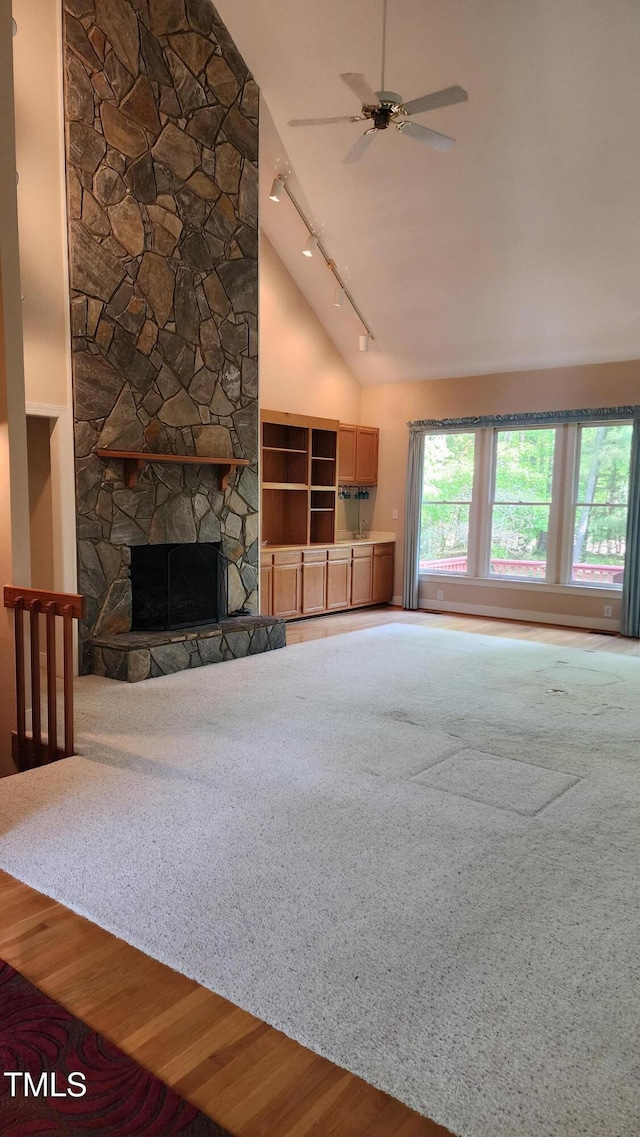 113 Colonial Dr, Wendell, NC 27591 - unfurnished living room with a ceiling fan, a stone fireplace, track lighting, high vaulted ceiling, and wood finished floors