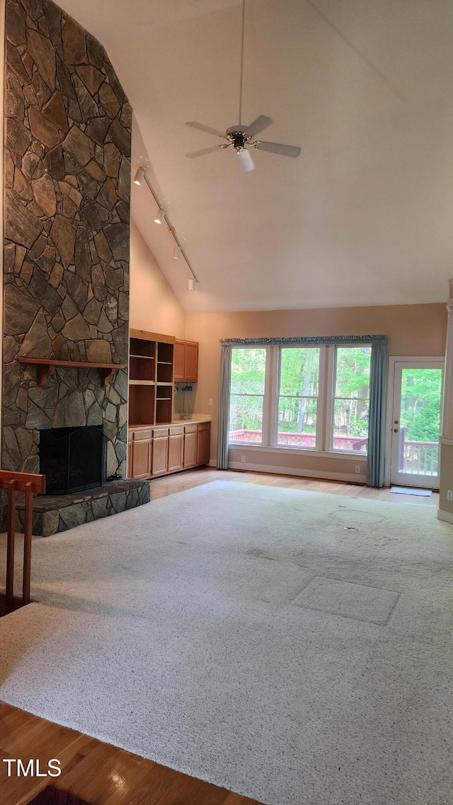 113 Colonial Dr, Wendell, NC 27591 - unfurnished living room featuring wood finished floors, a ceiling fan, high vaulted ceiling, rail lighting, and a stone fireplace