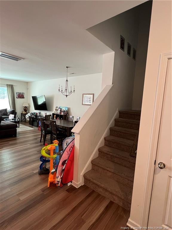 stairway featuring a notable chandelier, wood finished floors, and visible vents
