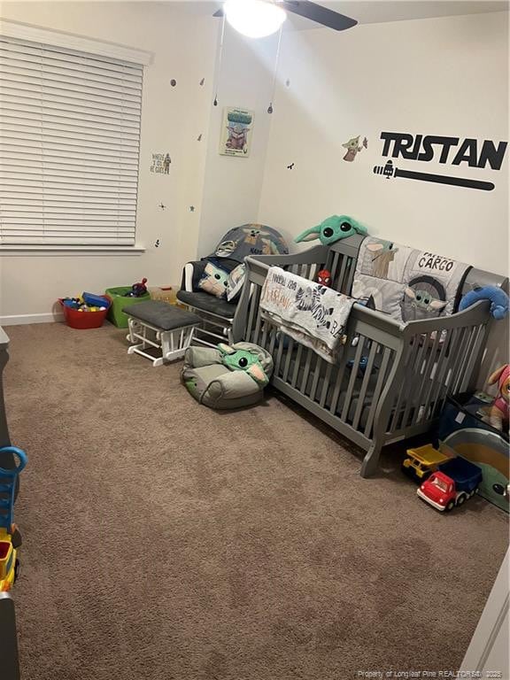 bedroom with a nursery area, carpet, and ceiling fan