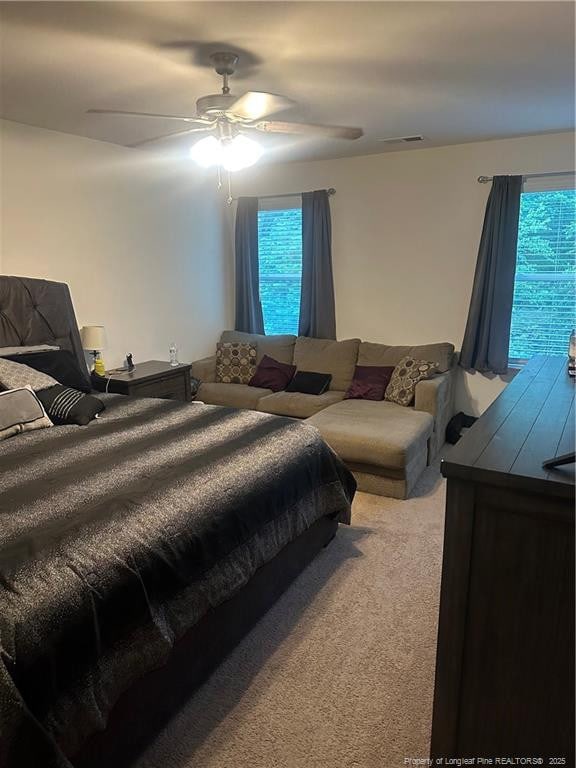 bedroom with ceiling fan, light carpet, multiple windows, and visible vents