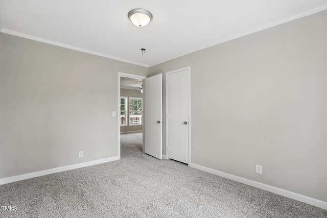 spare room featuring crown molding, baseboards, carpet floors, and ceiling fan