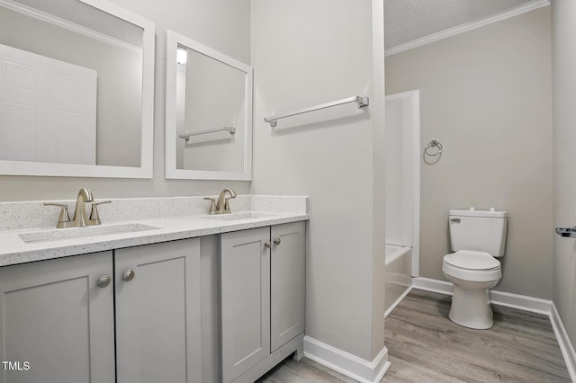 bathroom with crown molding, toilet, a sink, and wood finished floors