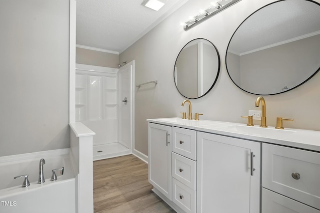 full bathroom featuring a textured ceiling, crown molding, a shower, wood finished floors, and a sink