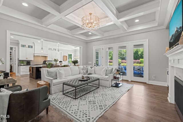 living area featuring a premium fireplace, beam ceiling, a chandelier, and a healthy amount of sunlight
