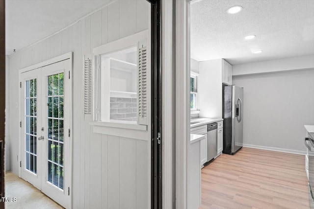 5124 Lazywood Ln, Durham, NC 27712 - kitchen featuring appliances with stainless steel finishes, a textured ceiling, french doors, light wood-type flooring, and white cabinetry