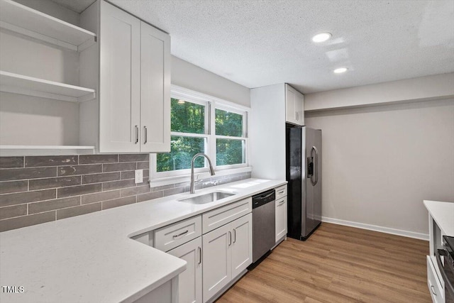 5124 Lazywood Ln, Durham, NC 27712 - kitchen with stainless steel appliances, open shelves, backsplash, white cabinetry, and light wood finished floors