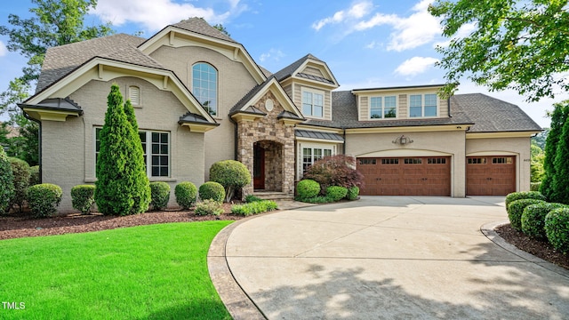 view of front of property with driveway, a front yard, a shingled roof, and stone siding