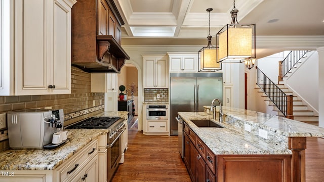 kitchen with stainless steel appliances, a sink, cream cabinetry, ornamental molding, and backsplash