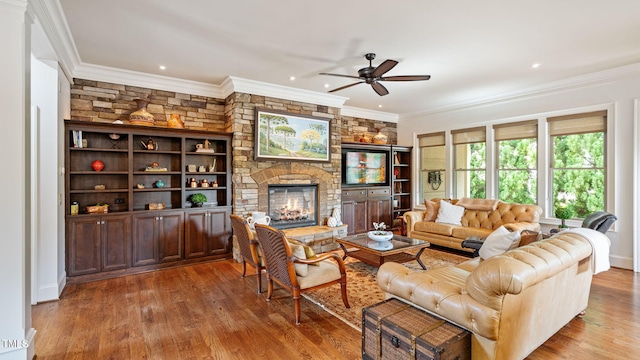 living area featuring ceiling fan, a stone fireplace, wood finished floors, crown molding, and recessed lighting