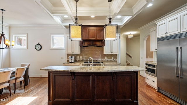 kitchen with stainless steel appliances, backsplash, a sink, wood finished floors, and ornamental molding