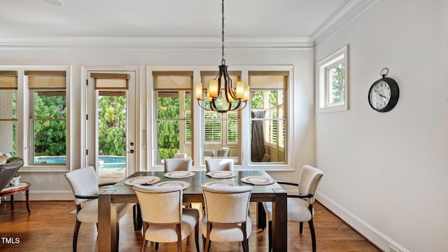 dining area with a chandelier, baseboards, wood finished floors, and crown molding