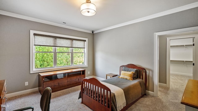 bedroom with light colored carpet, ornamental molding, baseboards, and a spacious closet