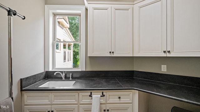 kitchen with a sink, dark countertops, and white cabinets