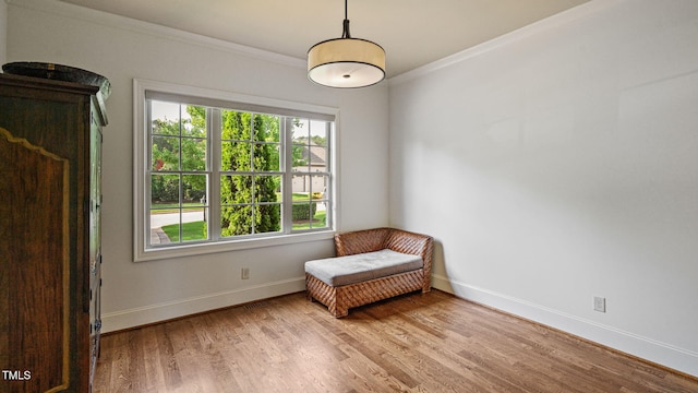 sitting room featuring wood finished floors, crown molding, and baseboards
