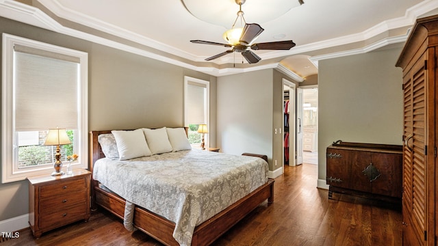 bedroom featuring a tray ceiling, baseboards, dark wood finished floors, and crown molding