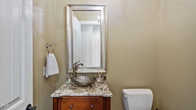 half bathroom featuring vanity and toilet