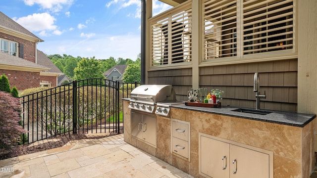 view of patio / terrace featuring exterior kitchen, a sink, grilling area, and fence