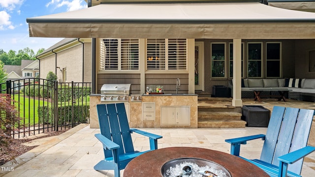 view of patio featuring grilling area, fence, an outdoor kitchen, an outdoor living space with a fire pit, and a sink