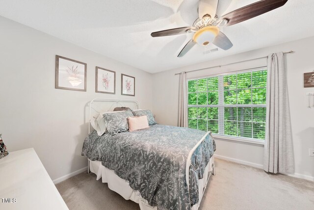 bedroom featuring light colored carpet, visible vents, a ceiling fan, and baseboards