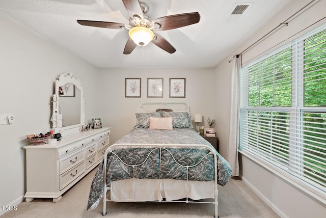 bedroom with a ceiling fan, visible vents, light carpet, and baseboards