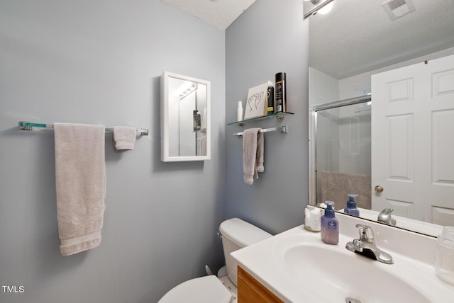 full bathroom featuring a textured ceiling, visible vents, toilet, a shower with shower door, and vanity
