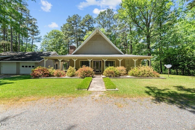 country-style home featuring a garage, covered porch, a chimney, and a front yard
