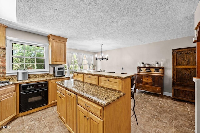 kitchen featuring oven, a textured ceiling, a chandelier, a center island, and a kitchen bar
