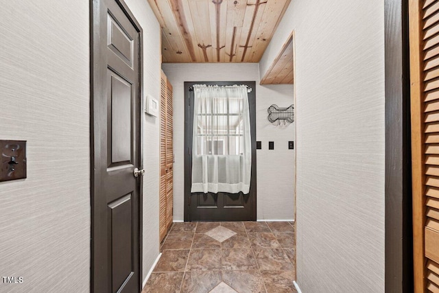 doorway to outside with wood ceiling, baseboards, and stone finish floor