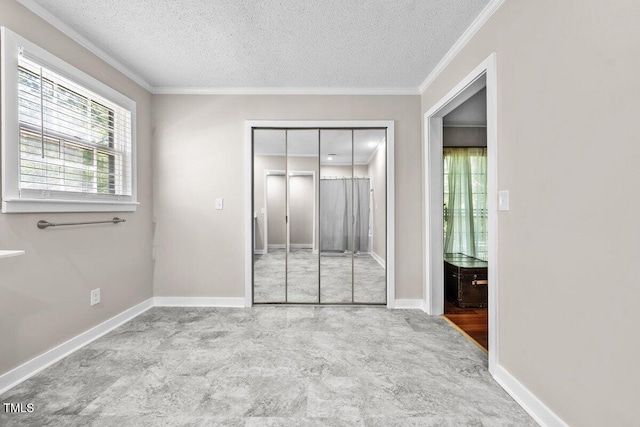 unfurnished bedroom with multiple windows, ornamental molding, a closet, and a textured ceiling