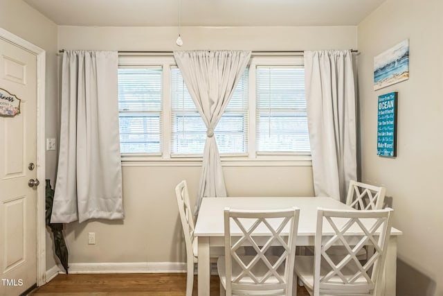 dining space with baseboards and wood finished floors