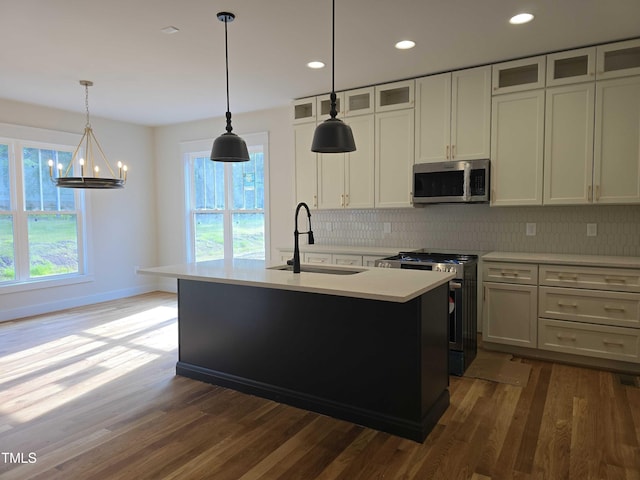 kitchen featuring stainless steel appliances, a sink, backsplash, dark wood-style floors, and healthy amount of natural light