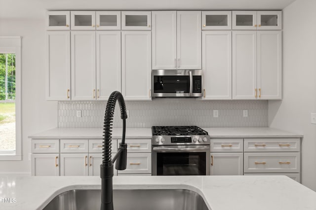 1005 Forrestal Pl, Durham, NC 27707 - kitchen with stainless steel appliances, tasteful backsplash, white cabinetry, and light stone countertops