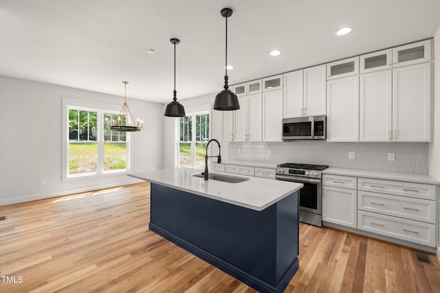 1005 Forrestal Pl, Durham, NC 27707 - kitchen featuring stainless steel appliances, tasteful backsplash, a center island with sink, light wood-style flooring, and white cabinets