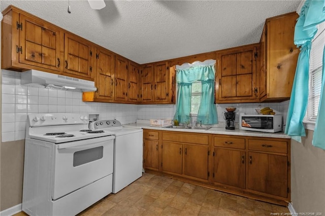 3042 Overhills Rd, Bunnlevel, NC 28323 - kitchen featuring under cabinet range hood, brown cabinets, white electric range oven, washer / dryer, and a textured ceiling