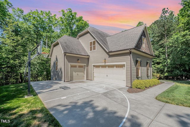 view of front of house featuring a garage, a front yard, a shingled roof, and driveway