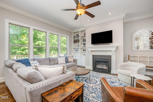 living room with a ceiling fan, crown molding, built in features, and wood finished floors