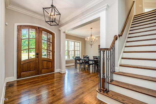 entrance foyer with french doors, ornamental molding, a chandelier, stairway, and dark wood-style floors