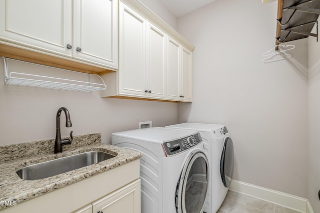 washroom with baseboards, independent washer and dryer, cabinet space, and a sink